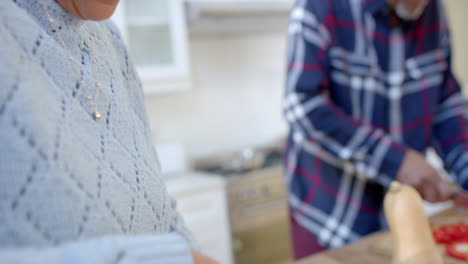 una pareja bi-racial feliz cocinando y cortando verduras en la cocina, en cámara lenta.