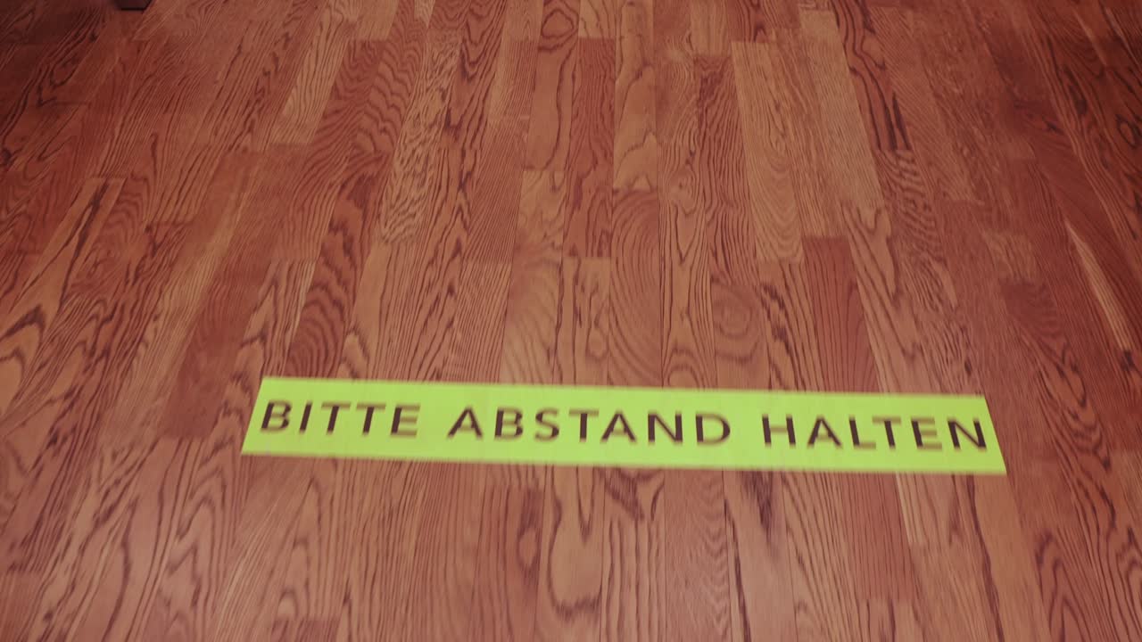 Camminando sopra i segnalatori di distanza per la coda Covid-19 "Bitte Abstand Halten"