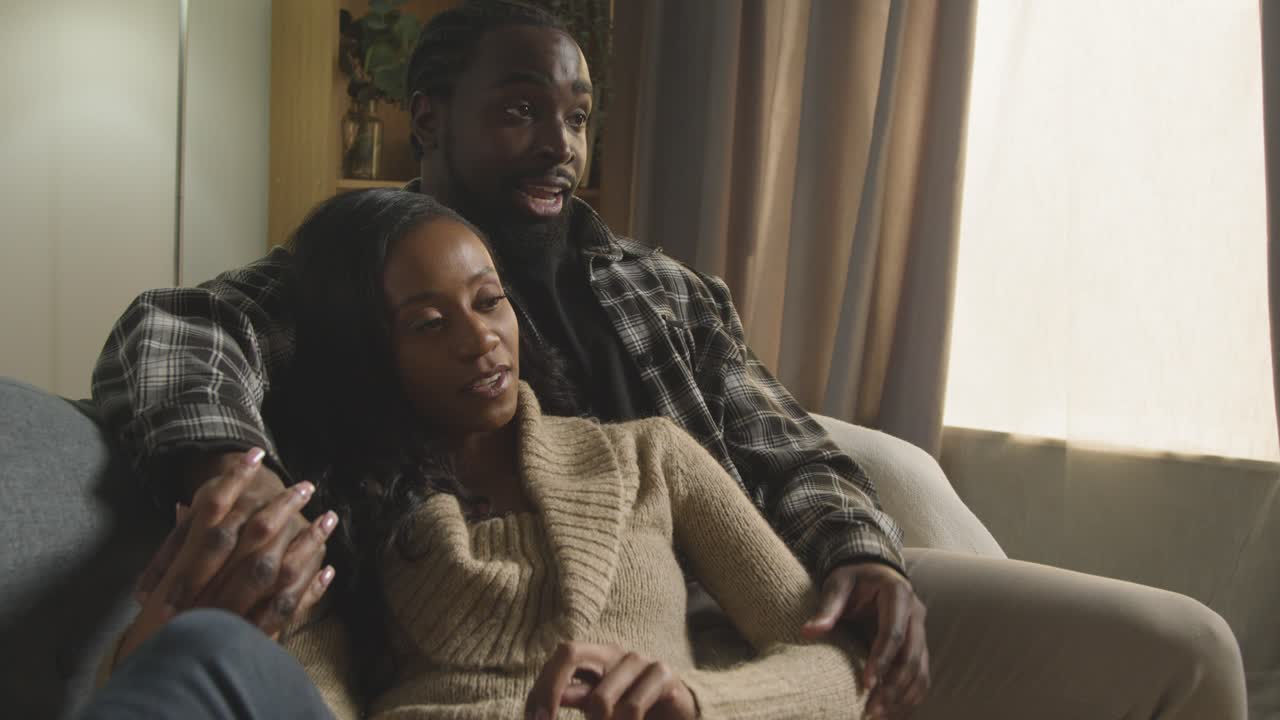 una joven pareja amorosa relajándose en casa sentada en el sofá viendo televisión juntos 4