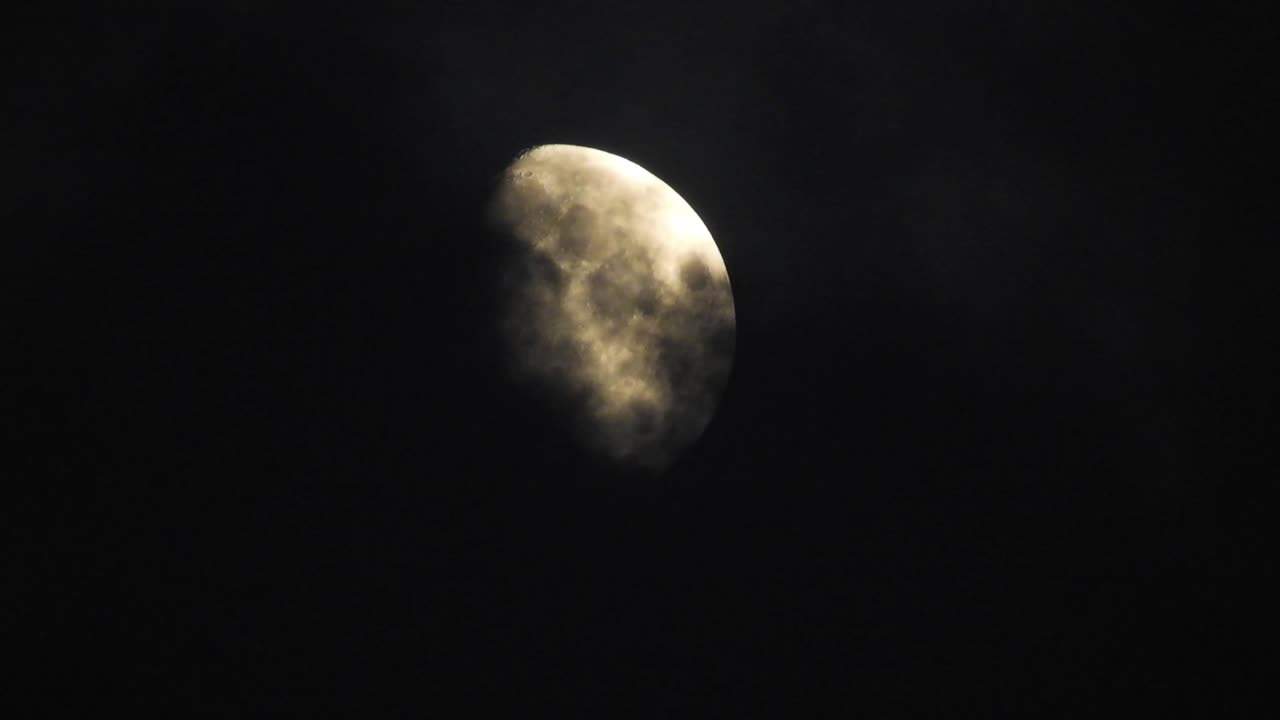 Moon at night with cloud real time. 4k video moon in the black sky.  Clouds passing by moon at night. night sky with cloudy weather