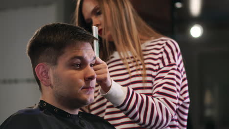 Hairdresser-tools.-Close-up-of-male-hands-brushing-electric-hair-clippers.-Hairdressers-prepare-hair-machine-for-next-client.-Man-clean-black-shaving-machine