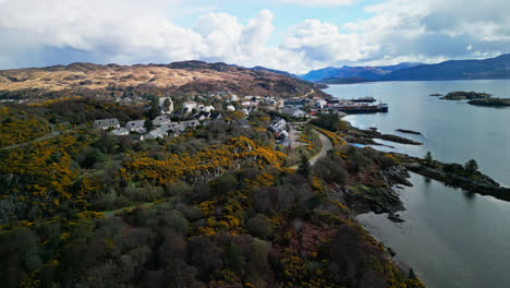 winding road of the skye crossing wraps below coastal villas in scotland on a cloudy day