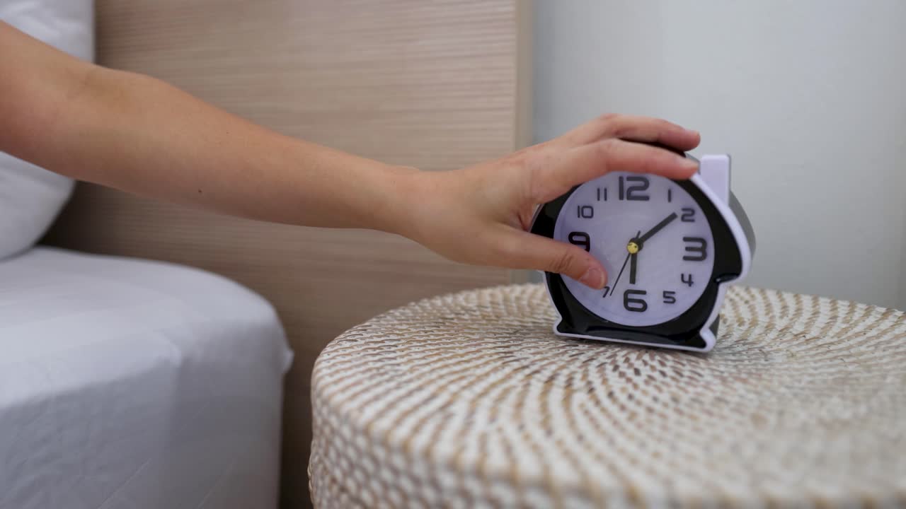 Mano che spegne la sveglia sul comodino al mattino