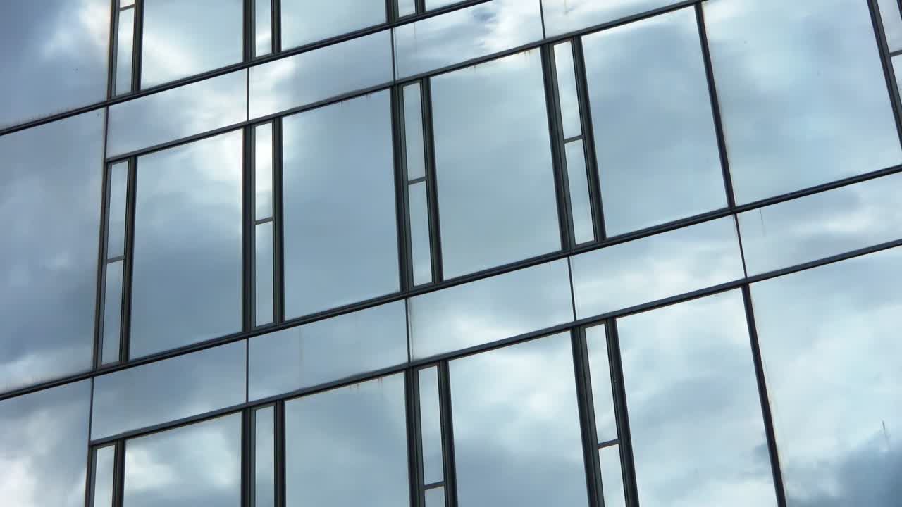 Time lapse of a blue summer sky with clouds reflecting off the glass facade of an office building