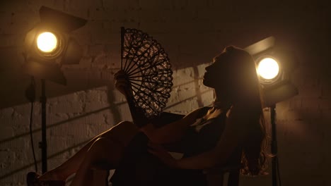 silhouette of a woman with fan in a studio setting