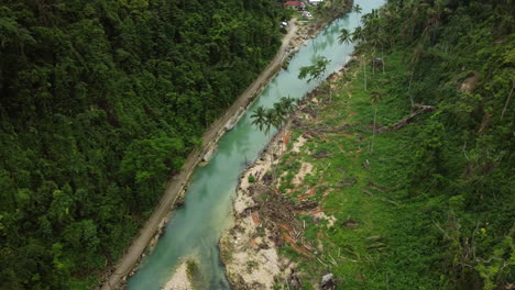 cinematic aerial shot moving down and turning up on a river in the tropical rainforest in cebu philippines revealing a house and abridge in asia, drone