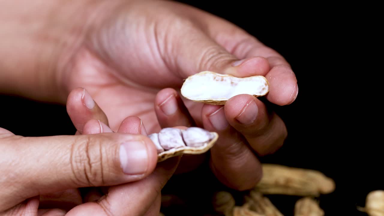 manos pelando una cáscara de maní abierta