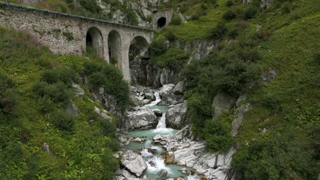 corriente de agua bajo el puente en la temporada de verano en el valle del paso de furka de suiza