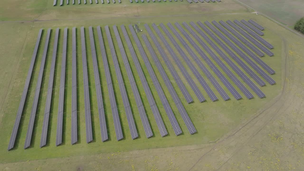 Shadow of clouds covers huge solar cell park in rows on a green farming field