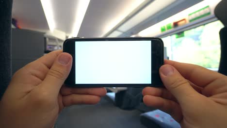 manos sosteniendo un teléfono con una pantalla blanca en el tren