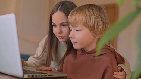 little boy and female teenager watching a movie with laptop and having fun at home