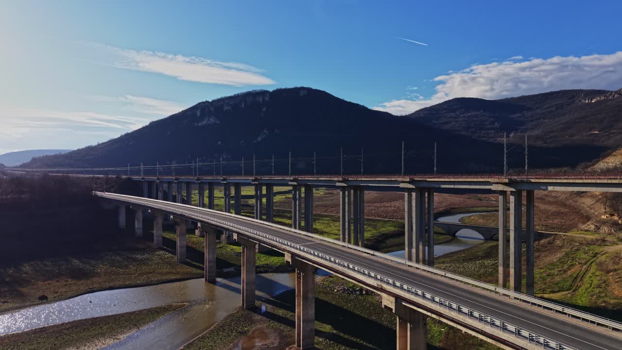 Ponte atravessando um rio perto de montanhas sob a luz forte da tarde
