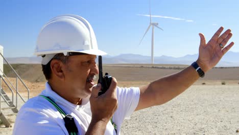 Male-engineer-talking-on-walkie-talkie-in-the-wind-farm-4k