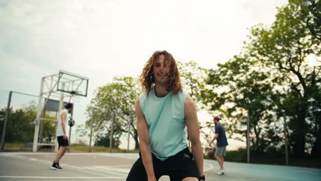 Retrato-De-Un-Hombre-Pelirrojo-De-Pelo-Rizado-Con-Una-Camiseta-De-Color-Claro-Que-Dribla-Hábilmente-Una-Pelota-De-Baloncesto-En-La-Cancha-De-Baloncesto-Afuera