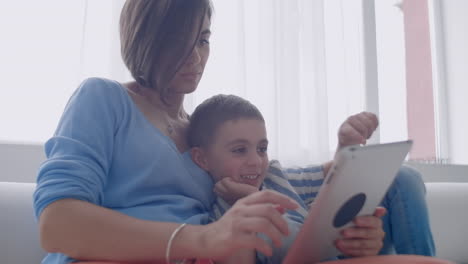 familia feliz madre y niño hijo usando tableta digital sentado en el sofá sonriente padre madre con hijo sosteniendo computadora mirando la pantalla hacer compras en línea hacer video llamadas ver dibujos animados