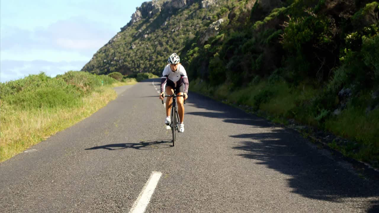 Ciclista donna che pedala su una strada di campagna 4k
