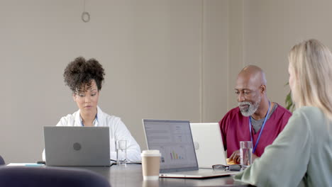 Diverse-doctors-using-laptops-in-meeting-room-with-copy-space,-slow-motion