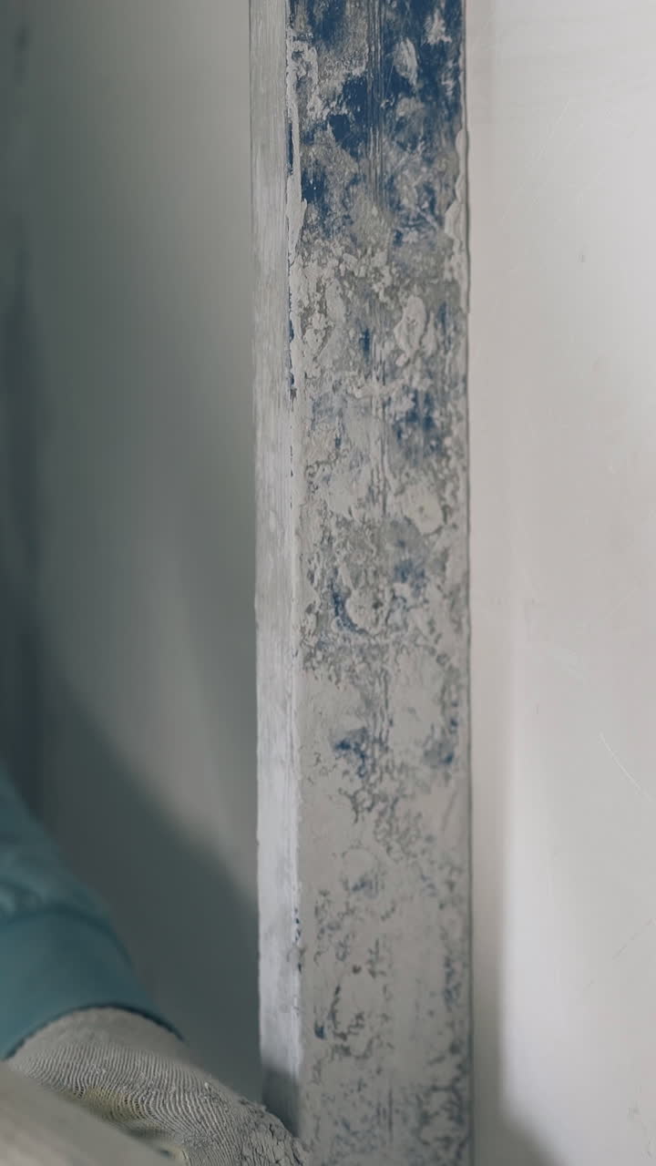 skilled repair worker aligns white gypsum plasterboard wall with long ruler extreme close view