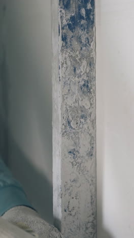 skilled repair worker aligns white gypsum plasterboard wall with long ruler extreme close view