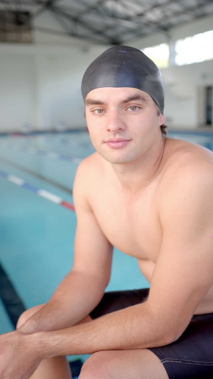 Vertical video: Swimmer in swim cap sitting by pool, preparing for training session