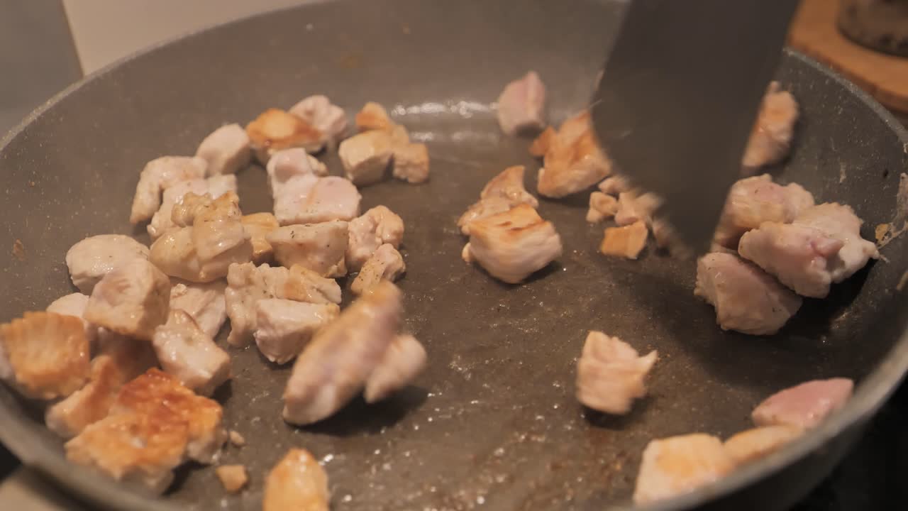 Diced turkey meat frying in a pan, stirred gently to cook evenly - 4K.