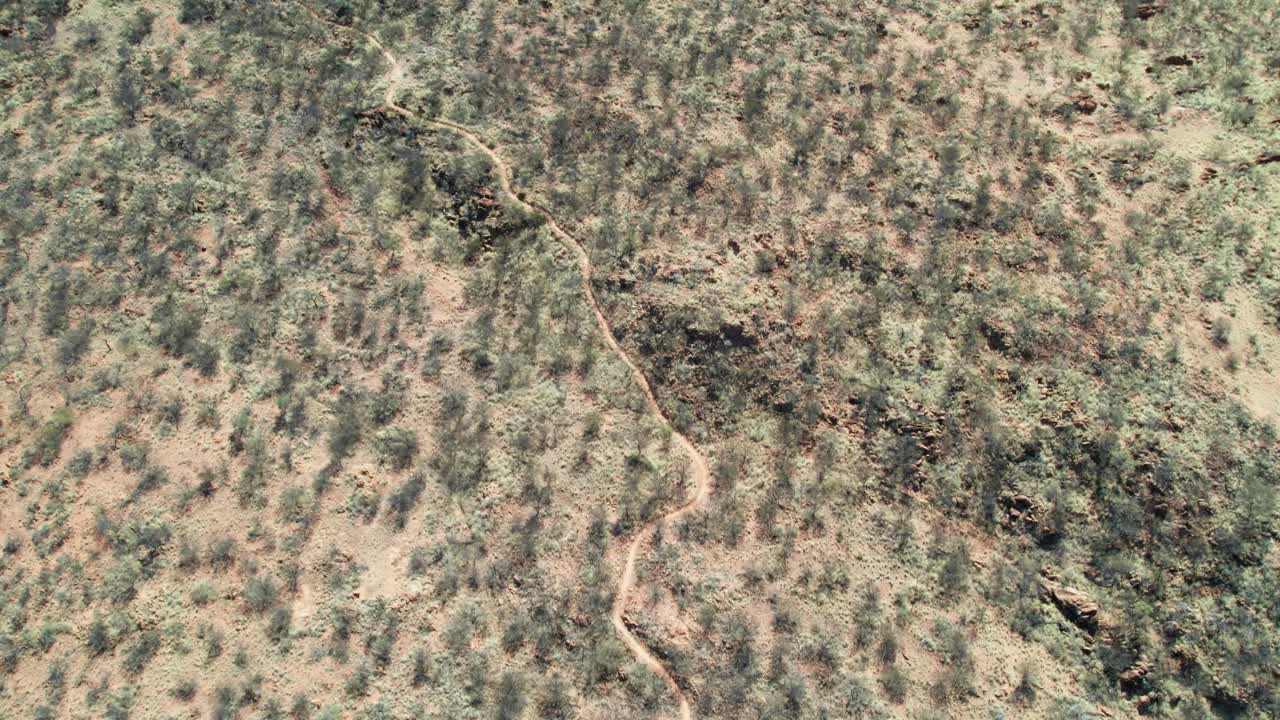 Aerial view of the Red Centre Way (track) at start of the Larapinta Trail (eastern end), north of Alice Springs, Mparntwe. Northern Territory, Australia. August 2022.