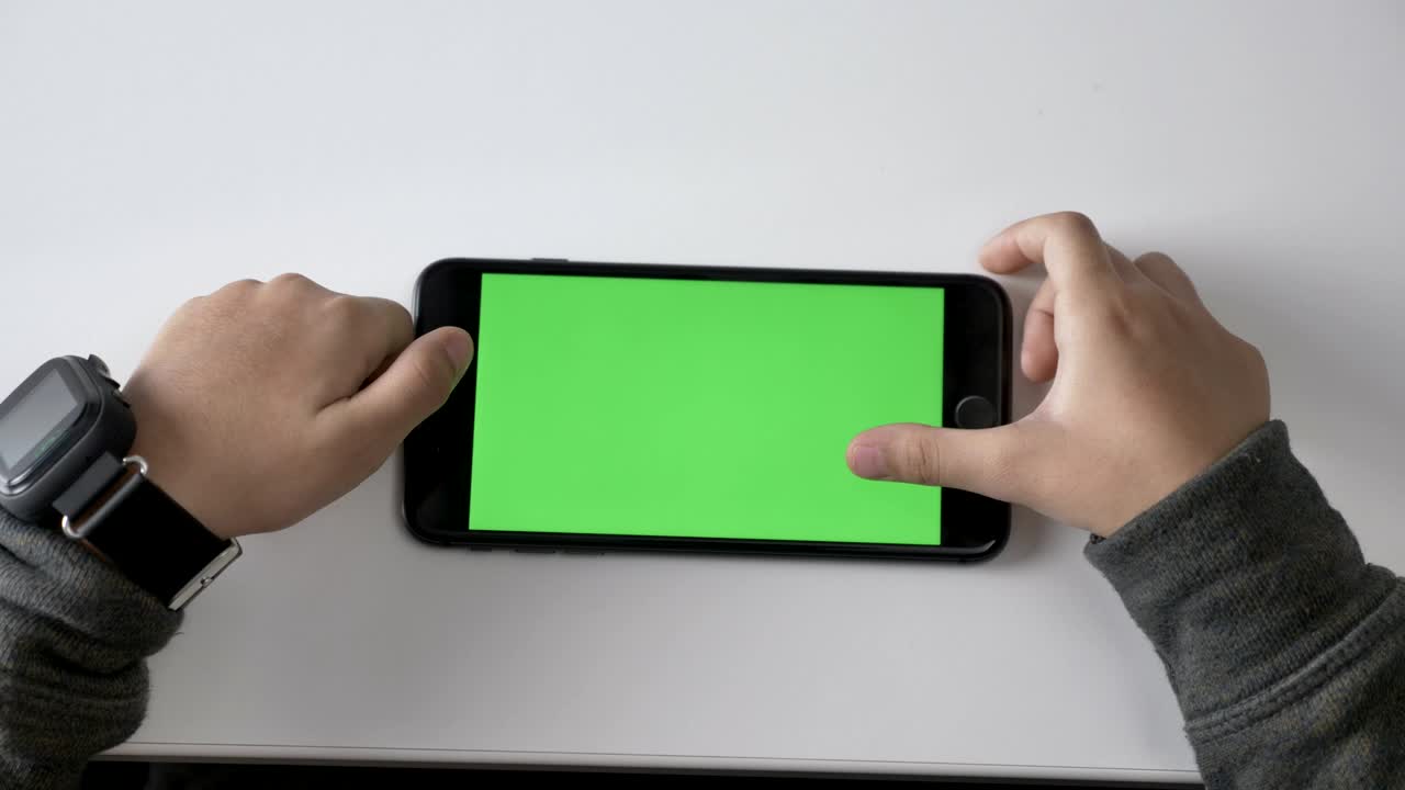 Children's hands playing on a smartphone, Green screen, chromakey concept, Top shot 60 fps