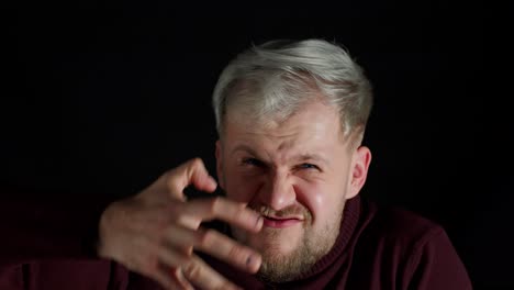 Portrait-of-angry-annoyed-young-man-screaming-to-the-camera-with-raised-hand-on-black-background