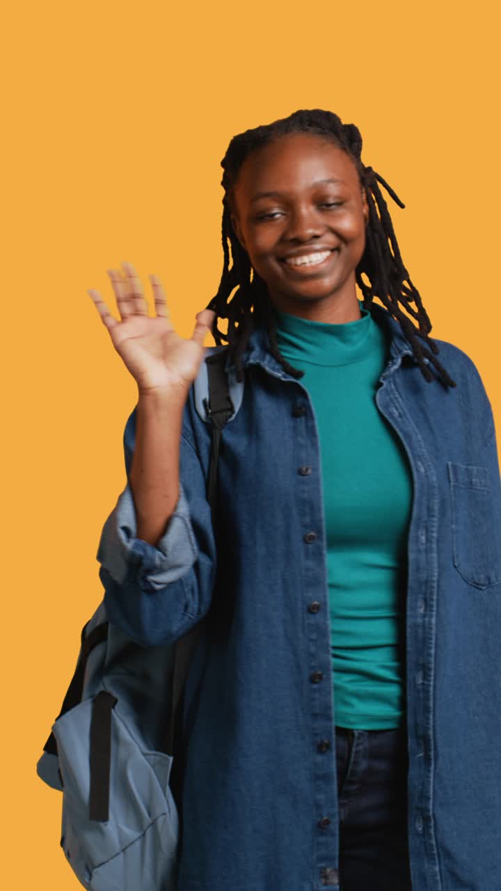 Friendly Young African American Woman Waving Hello with Backpack