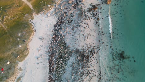 aerial view above beach and transparent, arctic sea, in norway - birdseye, drone shot, uttakleiv beach