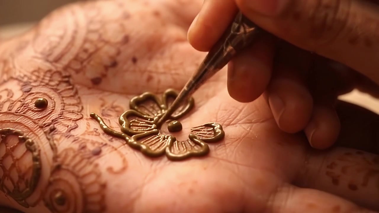 Artista applica un intricato disegno all'henné sul palmo della mano.