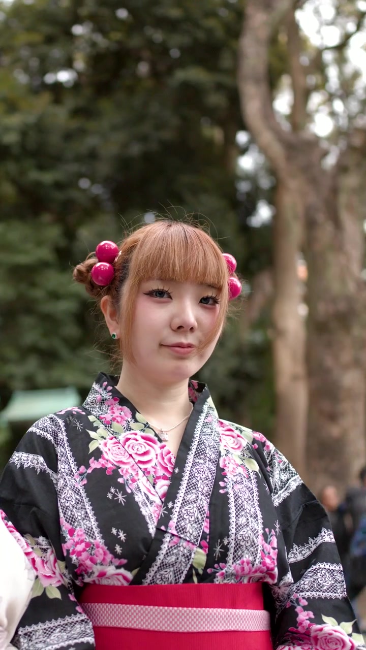 花柄の着物を着た日本人女性が、伝統的な神社の鳥居の近くで屋外でポーズをとる