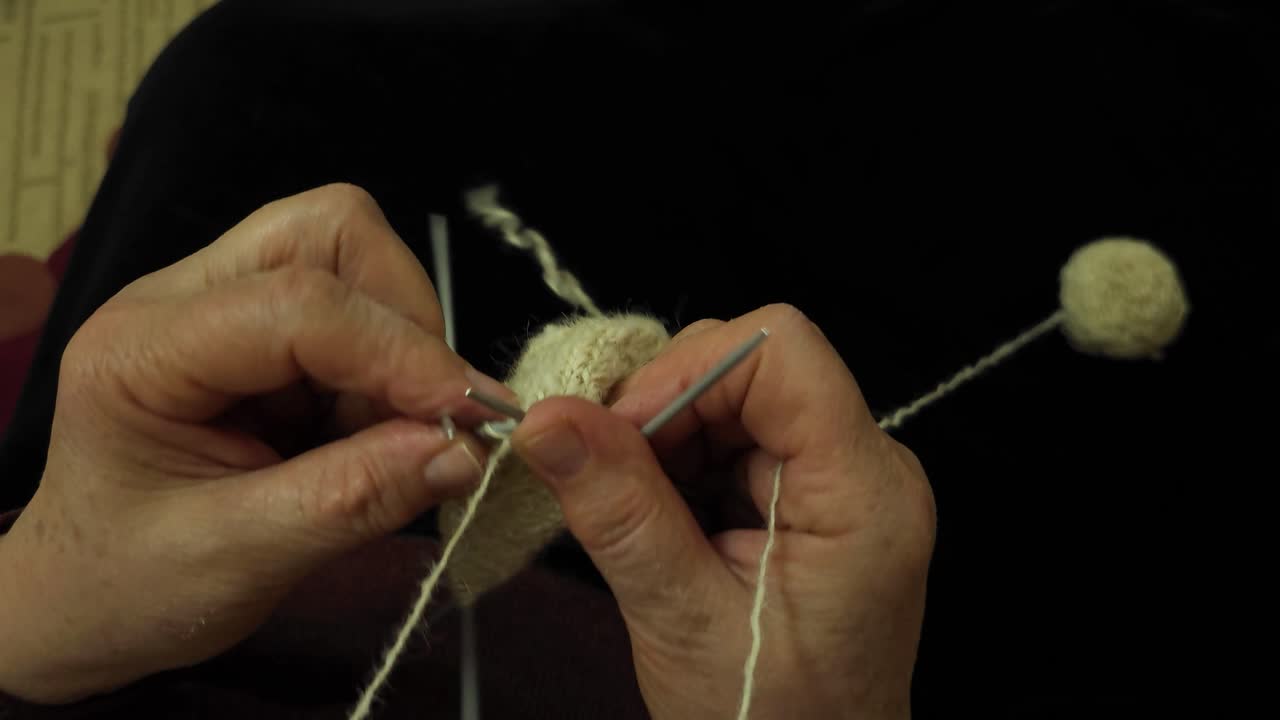 할머니는 천연 양털에서 편안함과 따뜻함을 불러일으키는 창으로 된 양털 양말을 능숙하게 수공예로 만니다.