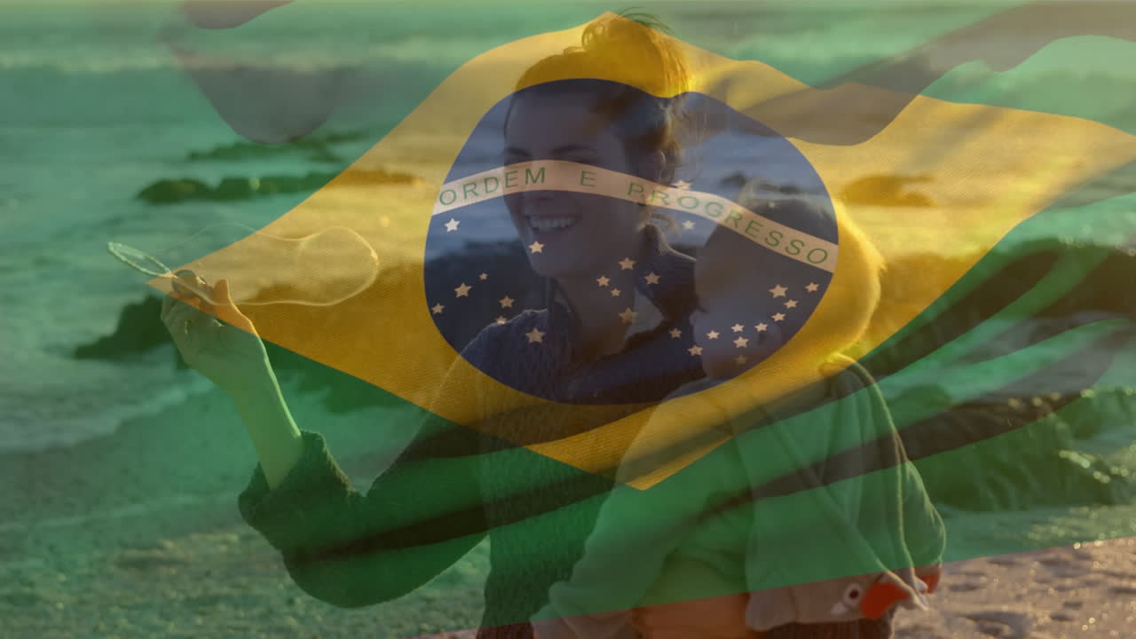 animación de la bandera de brasil sobre una madre caucásica feliz con un niño soplando burbujas en la playa