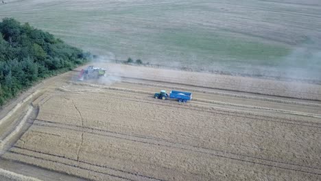 Una-Toma-Cinematográfica-De-Un-Dron-De-4k-De-Una-Cosechadora-Y-Un-Tractor-Cosechando-Un-Campo-En-Francia,-Mostrando-La-Agricultura