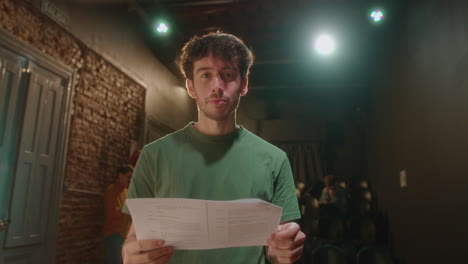 portrait of young actor with play script on theater stage