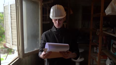 front portrait of young home inspector reviewing floor plans for renovation