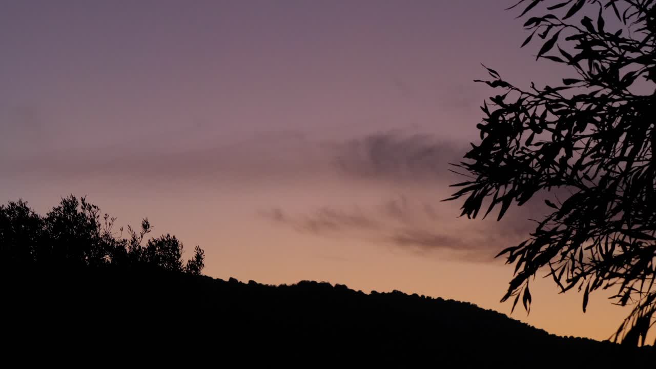 Soft purple sky after sunset with hills and tree in dark silhouette in the evening in Chia, Southern Sardinia, Italy