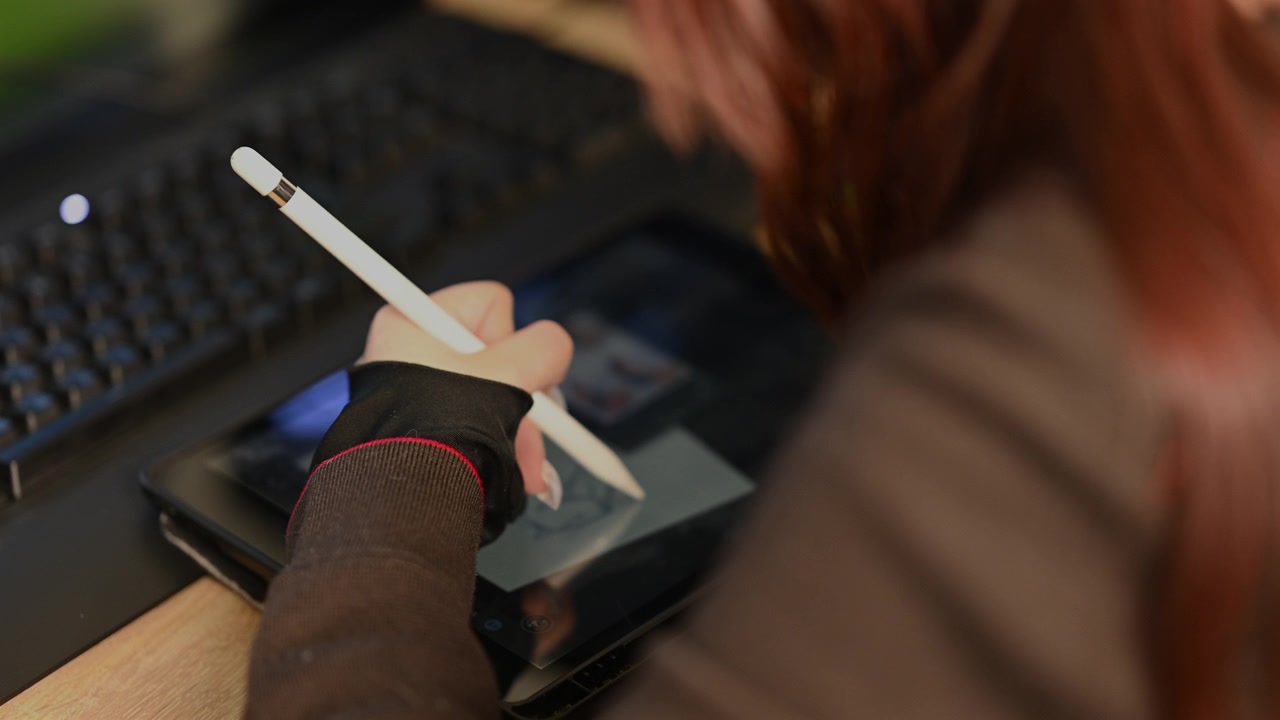 Close up of a student using a white stylus to draw a simple character sketch on a digital drawing tablet
