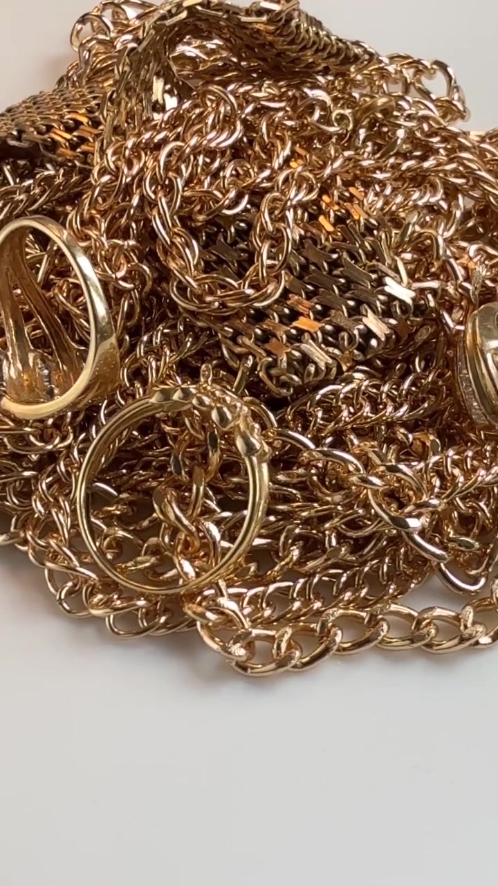 Cumulo di gioielli d'oro usati e rottami che ruota lentamente in primo piano