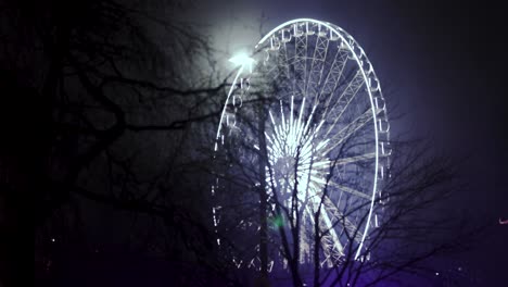 Ferries-Wheel-at-night,-bright-lights-Ferries-wheel,-trees-in-the-foreground,-night,-spinning-Niagara-Falls,-Canda