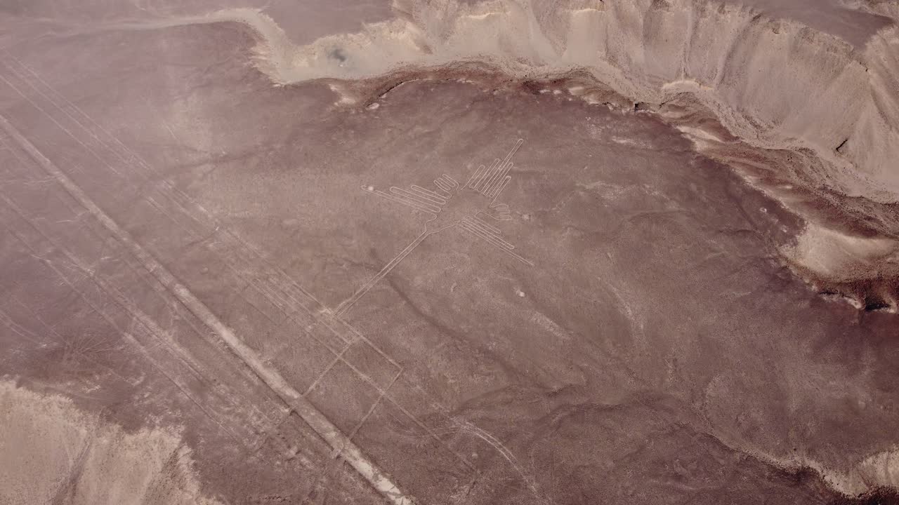Ancient geoglyph of a hummingbird part of the famous Nazca Lines. Drone flies high above looking down. Some long long linear geoglyphs can also be seen. Located in desert plateau in Nazca, Peru