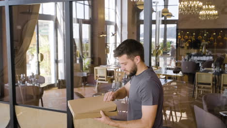 man opening the cardboard box to check pizza and then leaving the restaurant