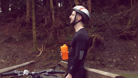 man drinking water next to bicycle