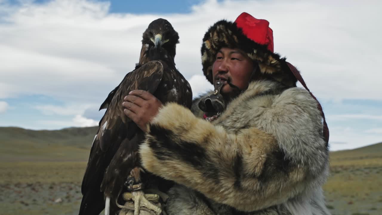 Golden eagle hunter spiritual bond with bird, caressing and stroking eagle, on horseback