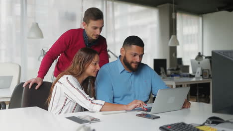 Smiling-young-managers-looking-at-laptop-in-office.