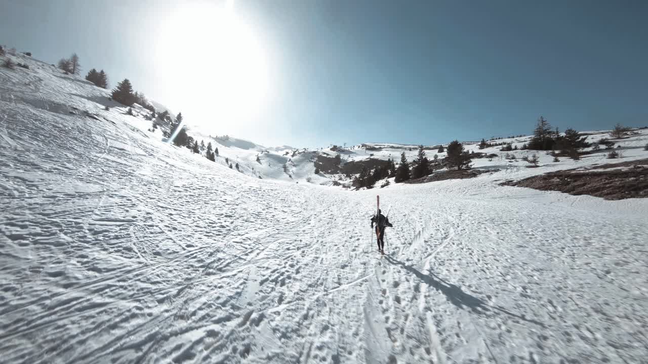 FPV shot circling around skier that is going up the snowy hill