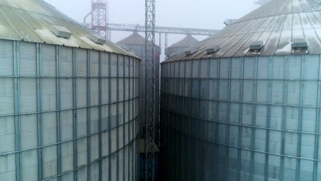 massive tanks of elevator storage factory. metal exterior of huge granary complexes on foggy day. support between the containers.