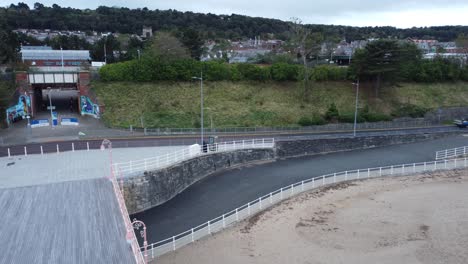 Colwyn-Bay-Welsh-seaside-town-pier-boardwalk-aerial-view-over-moody-overcast-sandy-low-tide-beach-pull-back-left