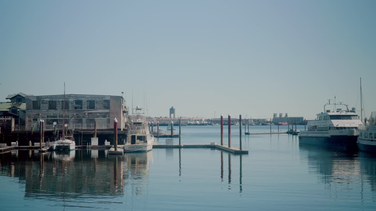 Beautiful view of Boston waterfront marina with boats docked at harbor, stunning reflections, blue skies and peaceful coastal scenery.